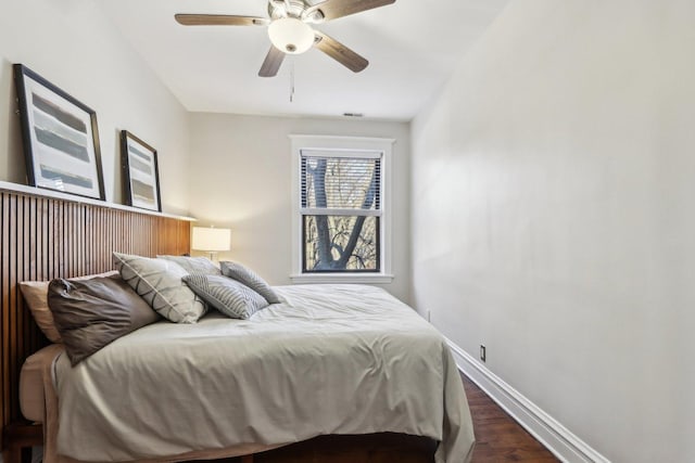 bedroom with dark wood-type flooring, a ceiling fan, visible vents, and baseboards