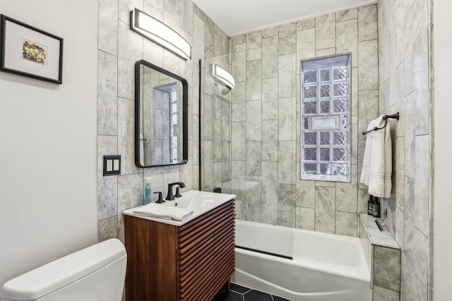 bathroom featuring toilet, vanity, tile patterned flooring, shower / bathtub combination, and tile walls