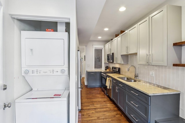 kitchen featuring stacked washer and clothes dryer, dark wood-type flooring, stainless steel appliances, open shelves, and a sink