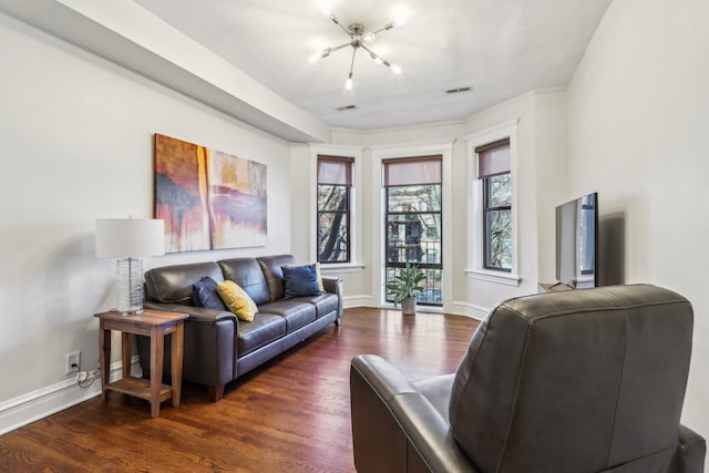 living area featuring dark wood-style flooring, visible vents, and baseboards