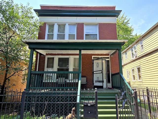 view of front of house with covered porch, brick siding, and fence