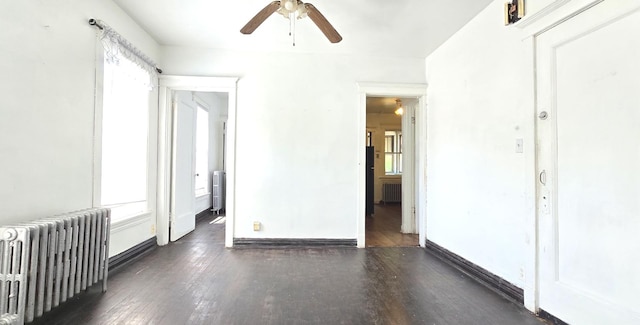 spare room featuring radiator heating unit, baseboards, and wood finished floors