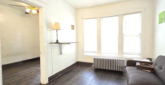 sitting room with radiator heating unit, baseboards, ceiling fan, and wood finished floors