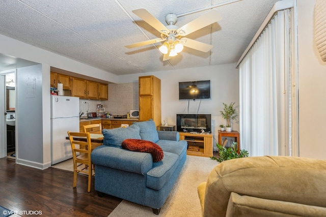 living area with dark wood-type flooring, ceiling fan, and a textured ceiling