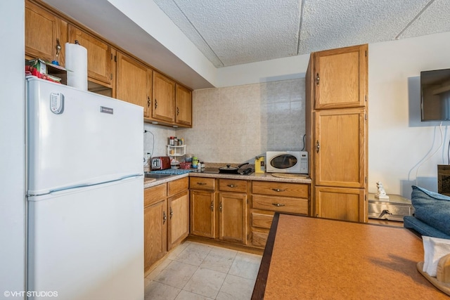 kitchen featuring white appliances, brown cabinetry, and light countertops