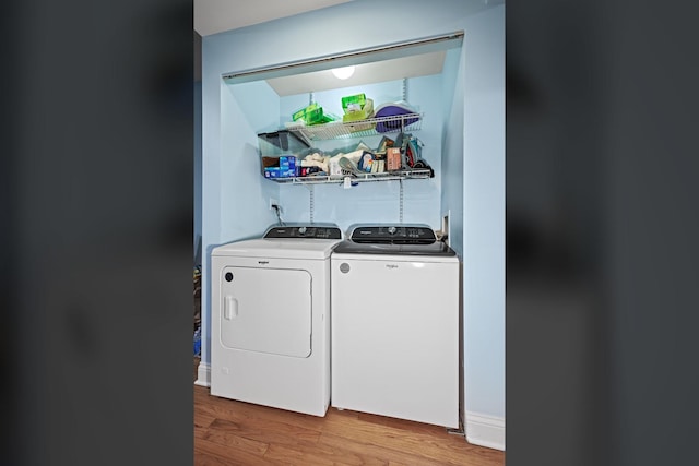 clothes washing area featuring laundry area, washer and clothes dryer, and wood finished floors