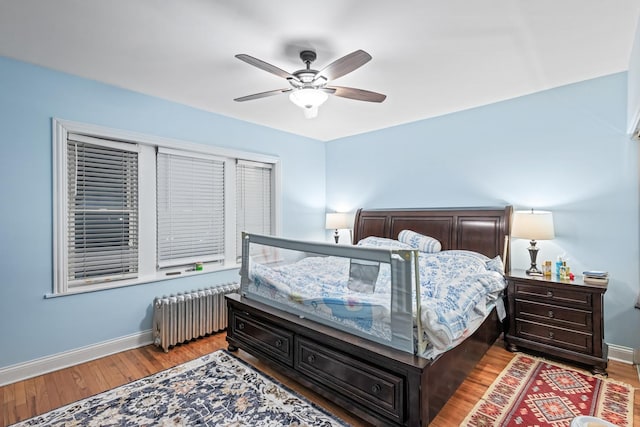 bedroom with radiator heating unit, baseboards, ceiling fan, and wood finished floors