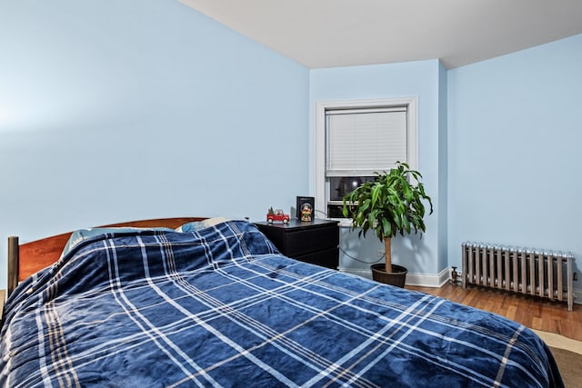 bedroom with baseboards, radiator heating unit, and wood finished floors