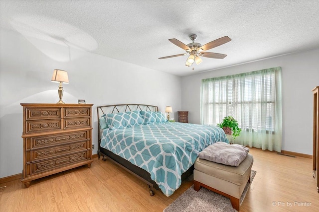 bedroom featuring a textured ceiling, light wood finished floors, and baseboards