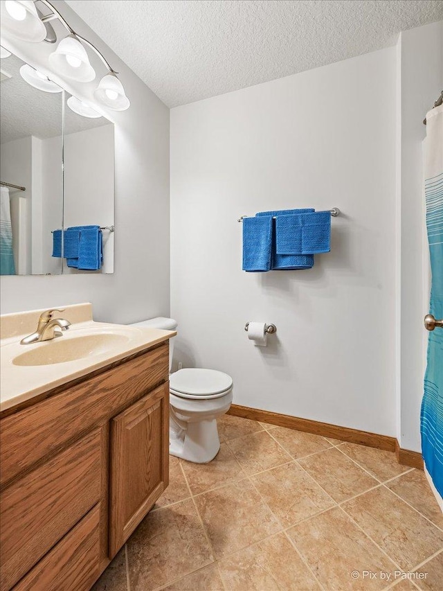 bathroom featuring baseboards, a textured ceiling, toilet, and vanity