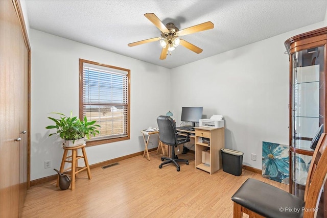 office space featuring light wood-type flooring, baseboards, visible vents, and a textured ceiling