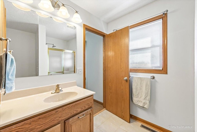 full bath featuring a stall shower, visible vents, vanity, and baseboards