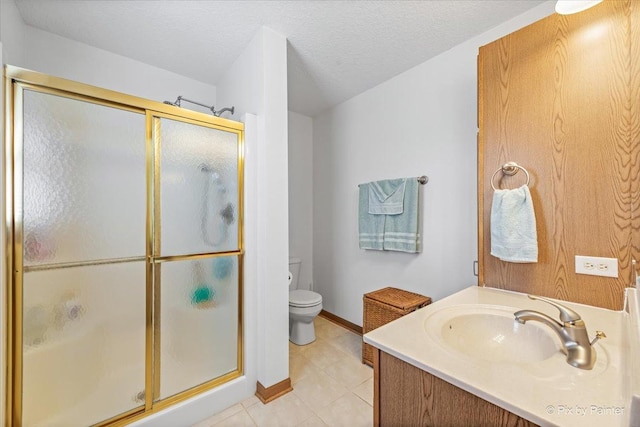 bathroom featuring toilet, a stall shower, a textured ceiling, vanity, and baseboards