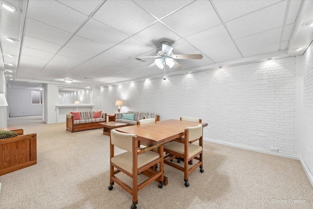 carpeted dining room featuring brick wall, a paneled ceiling, and a ceiling fan