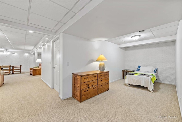 carpeted bedroom featuring a paneled ceiling, brick wall, and baseboards