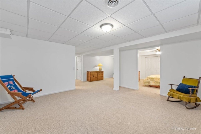 living area with a paneled ceiling, visible vents, and baseboards