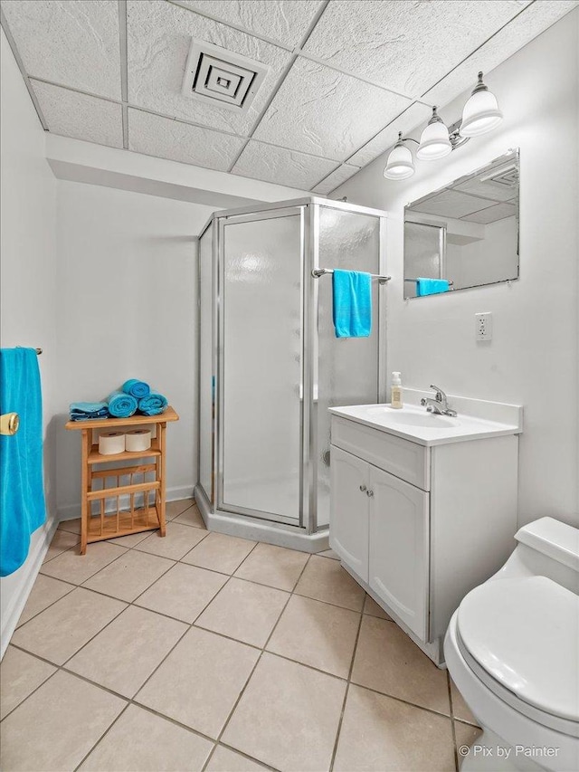 full bathroom with tile patterned flooring, toilet, a paneled ceiling, vanity, and a stall shower