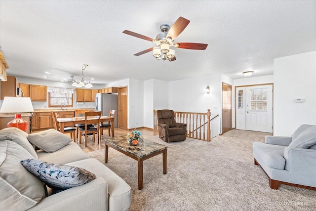 living room with light carpet, a textured ceiling, and a ceiling fan