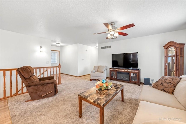 living room featuring light wood-style flooring, visible vents, a textured ceiling, and a ceiling fan