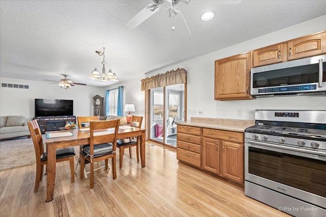 kitchen featuring light wood finished floors, appliances with stainless steel finishes, a textured ceiling, and ceiling fan with notable chandelier