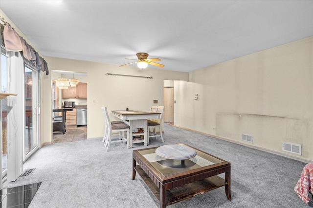 living area featuring visible vents, ceiling fan, and light carpet