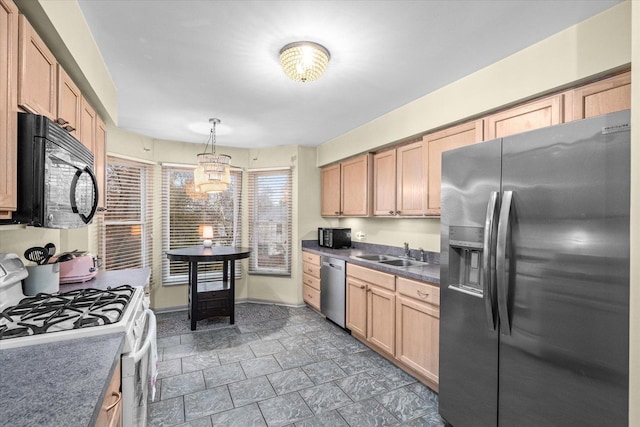 kitchen featuring dark countertops, appliances with stainless steel finishes, decorative light fixtures, light brown cabinets, and a sink