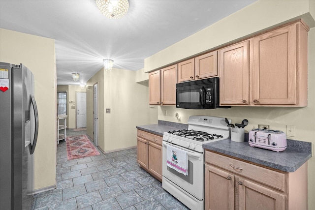 kitchen with black microwave, light brown cabinets, gas range gas stove, dark countertops, and stainless steel fridge