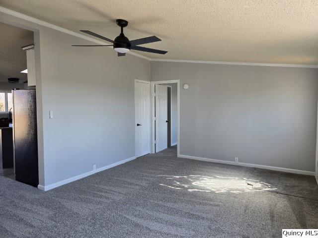 carpeted spare room with a textured ceiling, baseboards, and crown molding