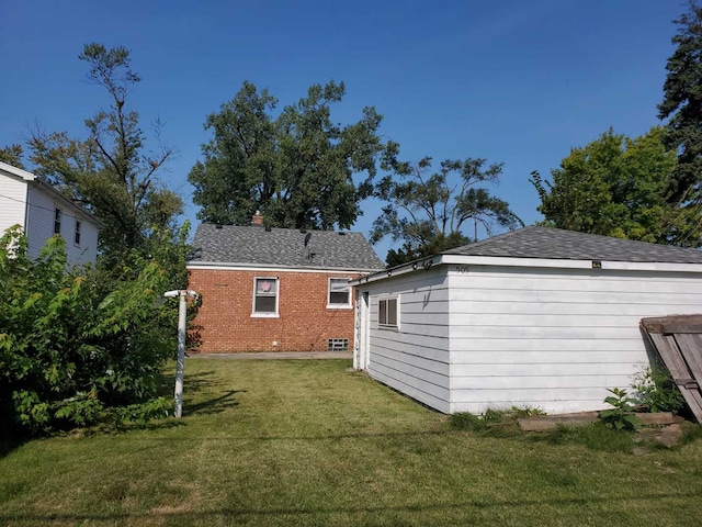 back of property with brick siding, a lawn, and an outdoor structure