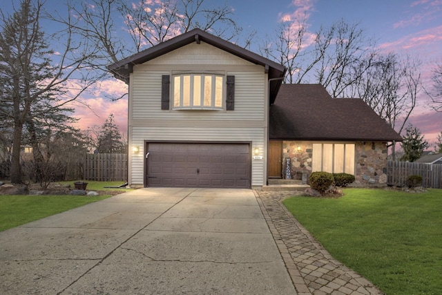 traditional-style home featuring a garage, a yard, fence, and driveway