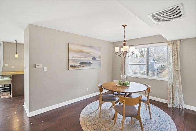 dining room featuring baseboards, visible vents, a notable chandelier, and hardwood / wood-style floors