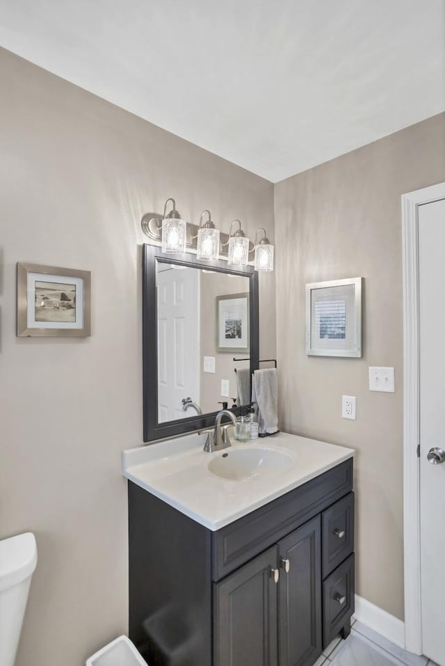 half bath featuring baseboards, vanity, and toilet