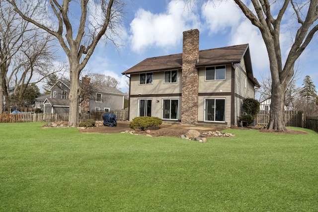 rear view of property with a chimney, fence, and a yard