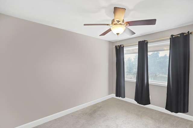 carpeted empty room with ceiling fan and baseboards