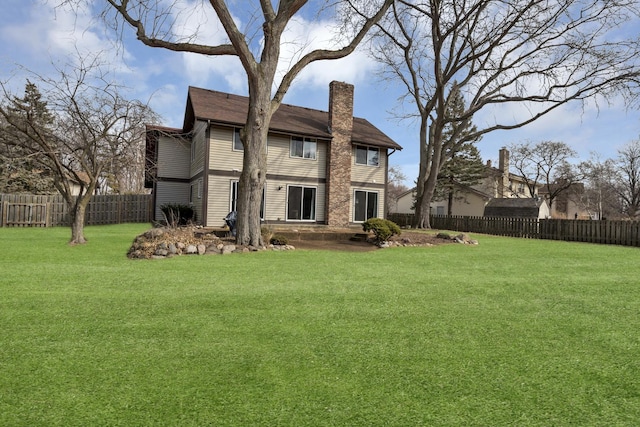 rear view of property with a chimney, fence private yard, and a lawn