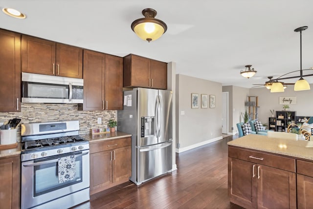 kitchen with stainless steel appliances, dark wood-style flooring, hanging light fixtures, and backsplash