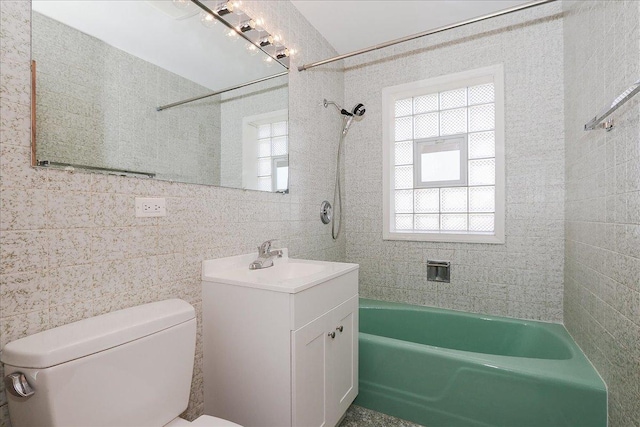 bathroom with shower / bathing tub combination, vanity, toilet, and tile walls