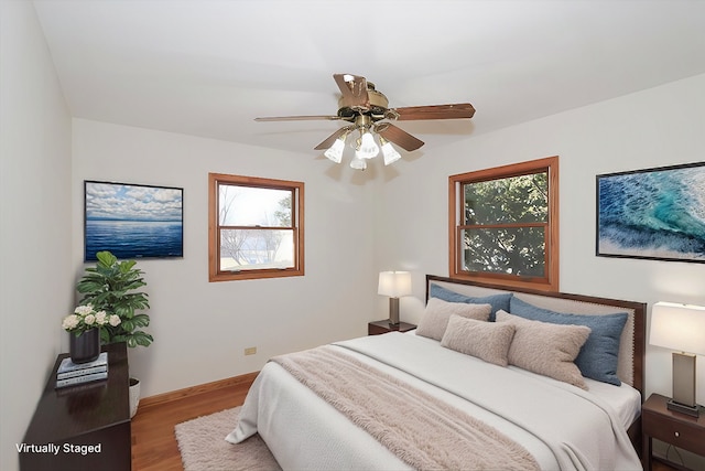 bedroom with wood finished floors, a ceiling fan, and baseboards