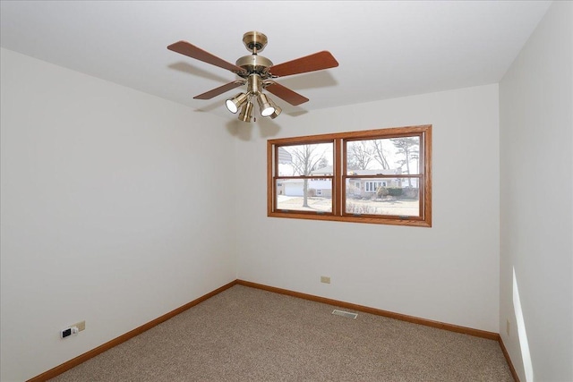 carpeted empty room featuring a ceiling fan, visible vents, and baseboards