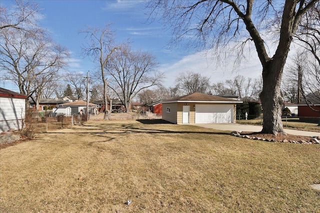 view of yard with a garage, driveway, fence, and an outdoor structure