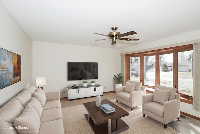 living area featuring a ceiling fan, light colored carpet, and baseboards