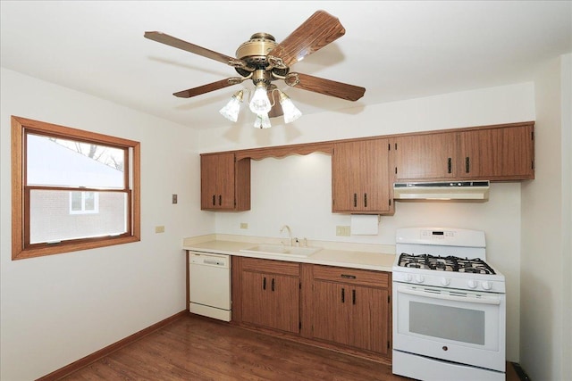 kitchen with white appliances, dark wood-type flooring, a sink, exhaust hood, and baseboards