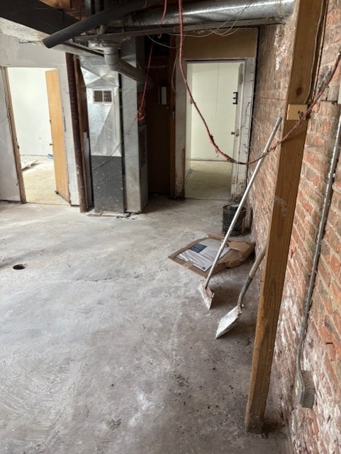 unfinished below grade area featuring heating unit and brick wall