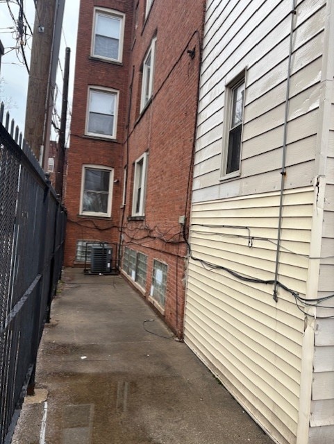 view of property exterior featuring central AC unit and fence