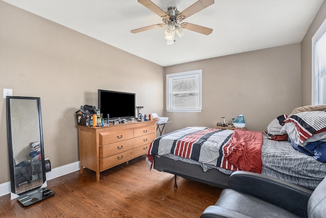 bedroom with multiple windows, wood finished floors, a ceiling fan, and baseboards