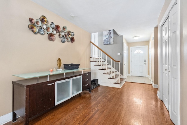 foyer with stairs, wood finished floors, and baseboards