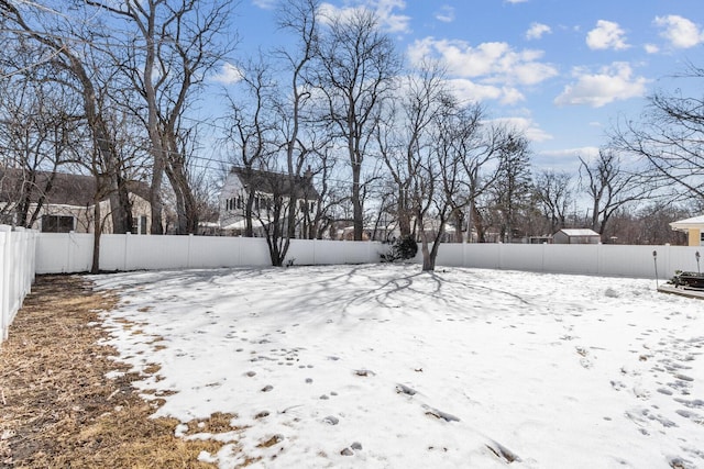 snowy yard with a fenced backyard