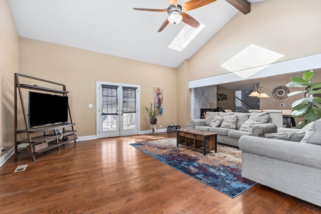 living area featuring visible vents, baseboards, stairway, wood finished floors, and high vaulted ceiling