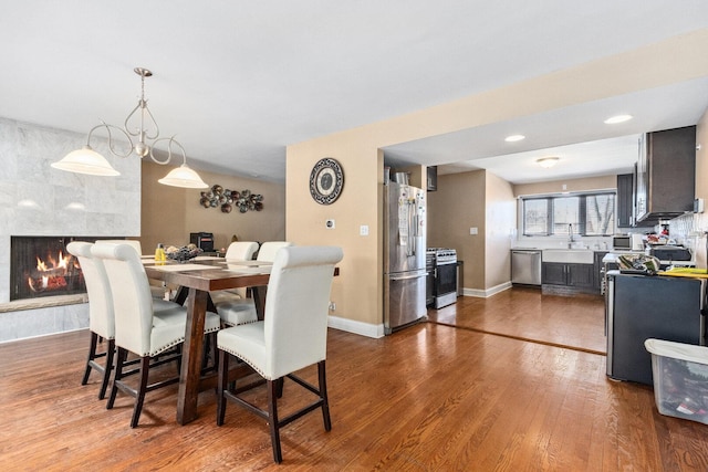 dining area featuring recessed lighting, a large fireplace, baseboards, and wood finished floors