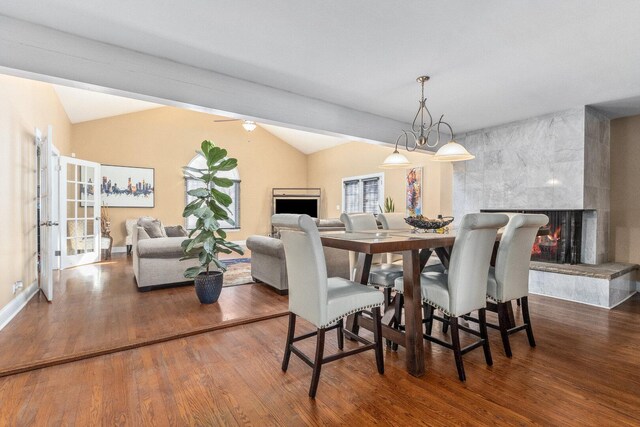 dining space featuring vaulted ceiling, a fireplace, and wood finished floors